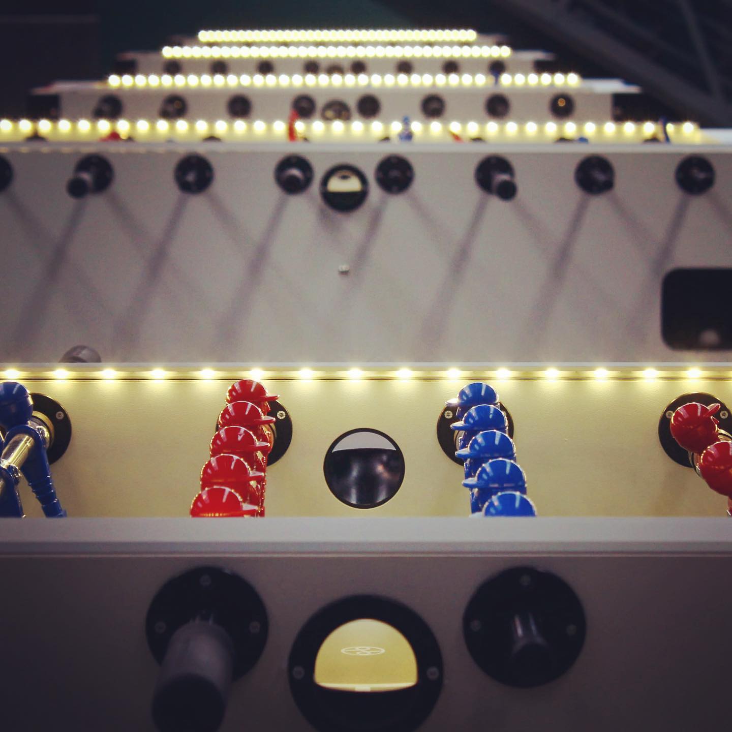 Beleuchteter Tischkicker mit roten und blauen Figuren unter dem LED-Glow von kickerdelight